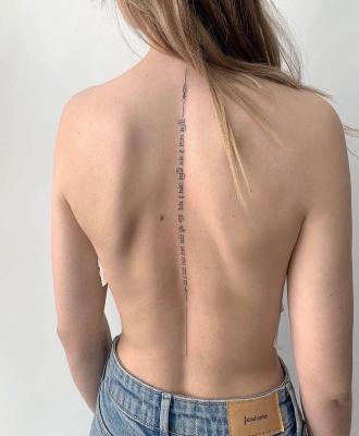 Damski tatuaż napis wzdłuż kręgosłupa