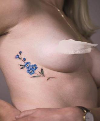 Kwiatek koło piersi kobiecy tatuaż