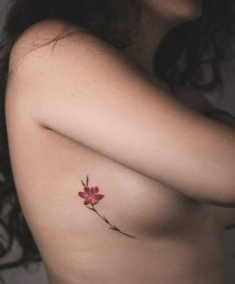 Tatuaż czerwony kwiatek pod piersią