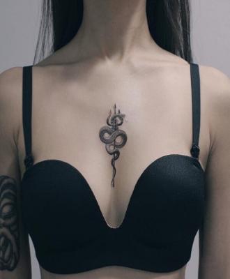 Tatuaż damski mały wąż między piersiami
