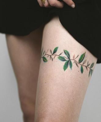 Tatuaż owijka gałązka damski na udzie