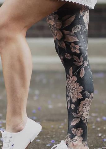 Damski ciemny tatuaż na jednej nodze