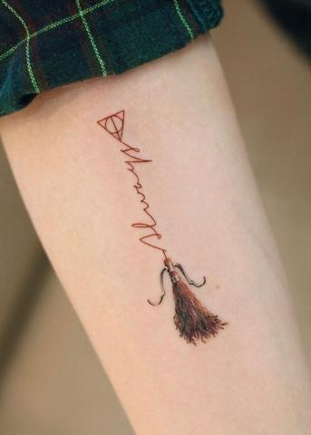 Damski tatuaż miotła i napis