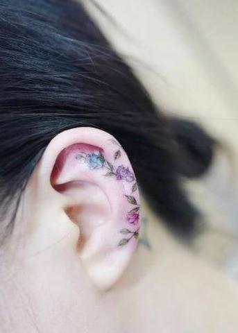 Na uchu tatuaż kolorowe kwiaty