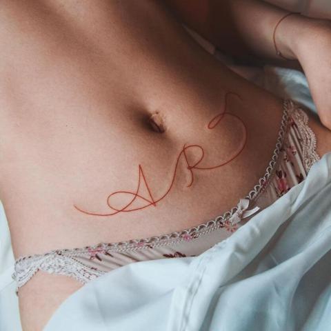 Tatuaż czerwony napis na brzuchu